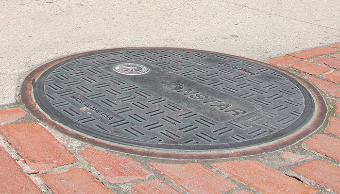 EJ DUROSTREET composite cover in iron frame in sidewalk with brick